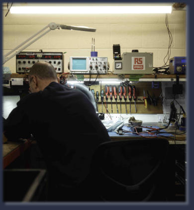 Technician performing industrial electronic repair on PLC unit at Neutronics NE Ltd