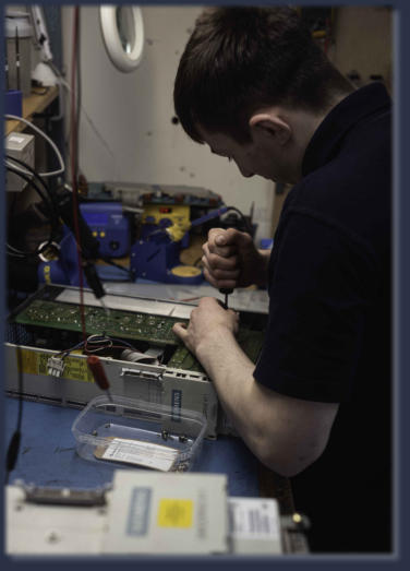 Neutronics engineer repairing industrial electronic control unit at workstation