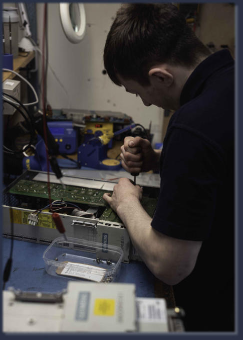Neutronics engineer repairing industrial electronic control unit at workstation